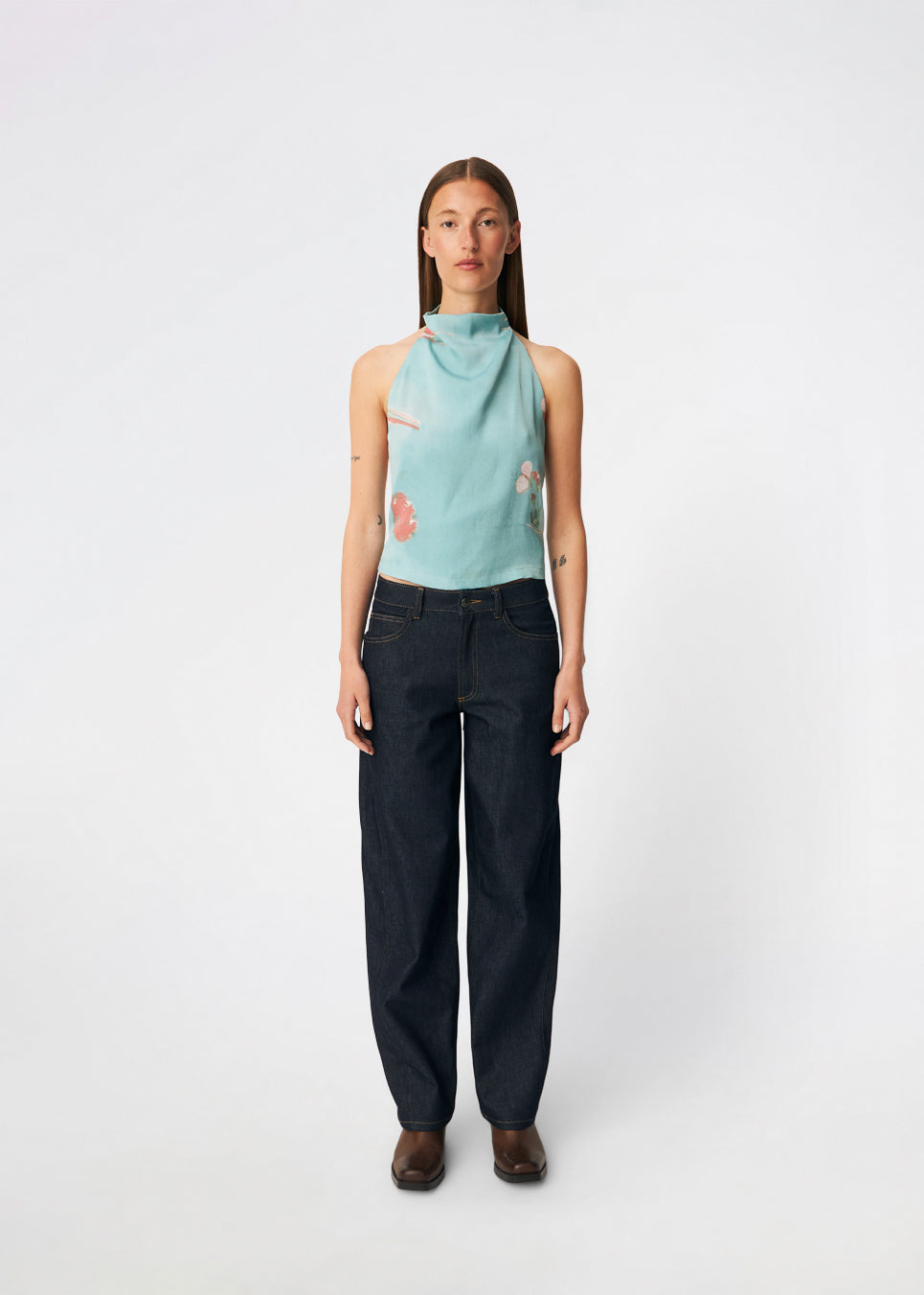 Elegant halterneck-top med et kunstnerisk print og et feminint udtryk. Carinamd print top er designet i en let, glat kvalitet med en høj halterneck-udskæring, der lukkes i nakken, og et bindebånd i ryggen, som giver en smuk og justerbar pasform. Det draperede design og det unikke print gør toppen til et iøjnefaldende valg til både festlige lejligheder og sommerens elegante outfits.