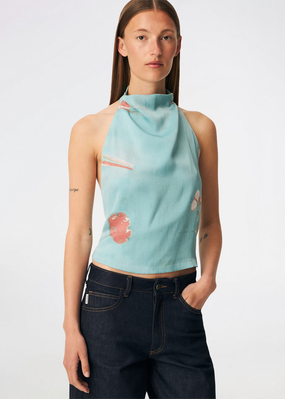 Elegant halterneck-top med et kunstnerisk print og et feminint udtryk. Carinamd print top er designet i en let, glat kvalitet med en høj halterneck-udskæring, der lukkes i nakken, og et bindebånd i ryggen, som giver en smuk og justerbar pasform. Det draperede design og det unikke print gør toppen til et iøjnefaldende valg til både festlige lejligheder og sommerens elegante outfits.