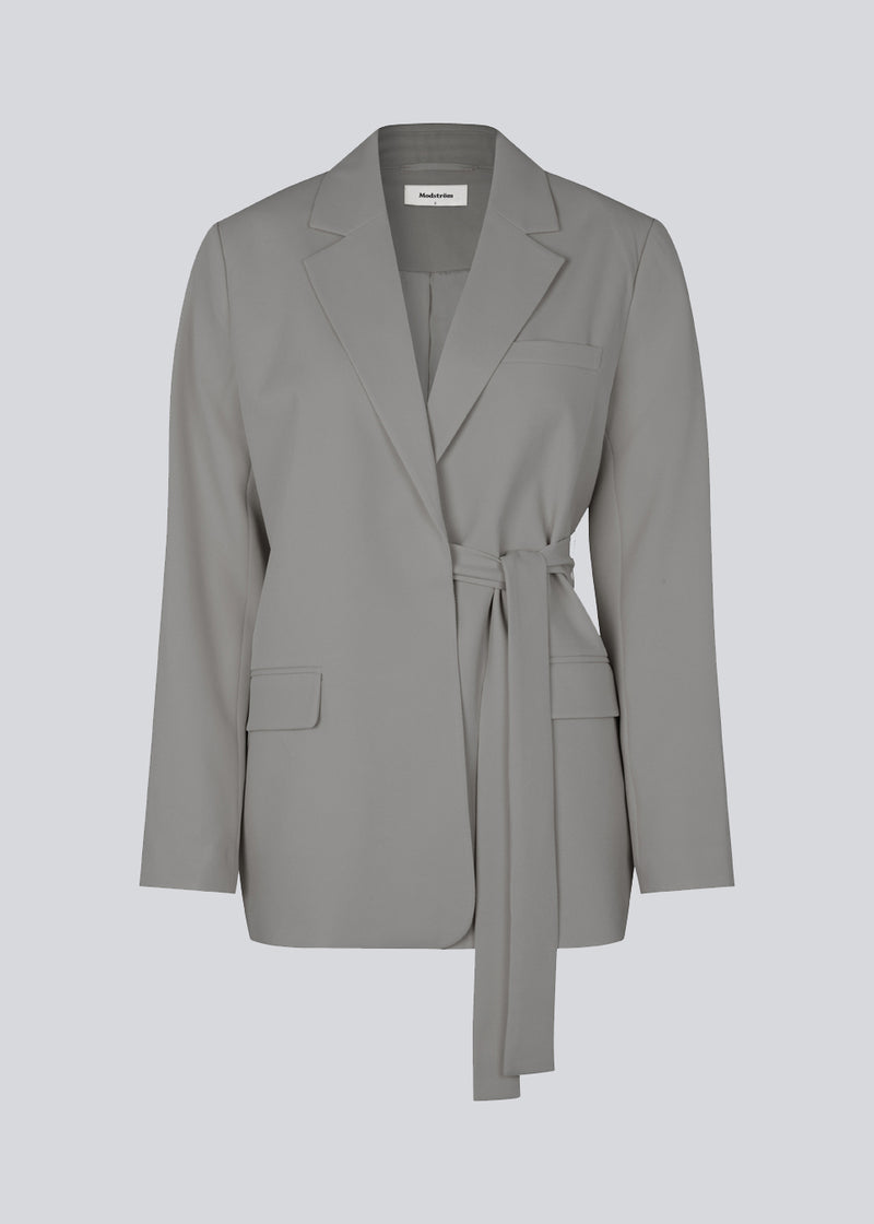 CayaMD blazer i grå har en afslappet pasform med klassiske detaljer med et twist med bindebælte i taljen. Fremstillet af genanvendte materialer. Style med de matchende bukser: GrayMD pants i samme farve.