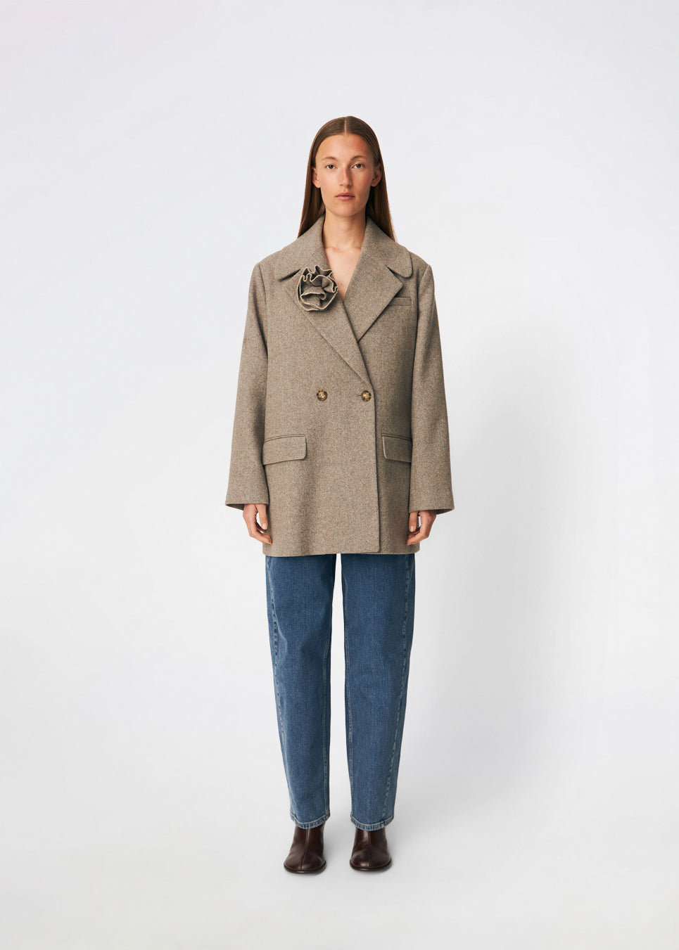 Cecarmd Jacket er en klassisk dobbeltradet jakke med en afslappet, oversized pasform. Designet er fuldendt med brede revers, klaplommer og en aftagelig blomsterbroche, som tilfører et feminint og dekorativt element. Den bløde uldblanding gør jakken ideel som overgangsjakke eller som et elegant lag over sæsonens strik og tailoring.