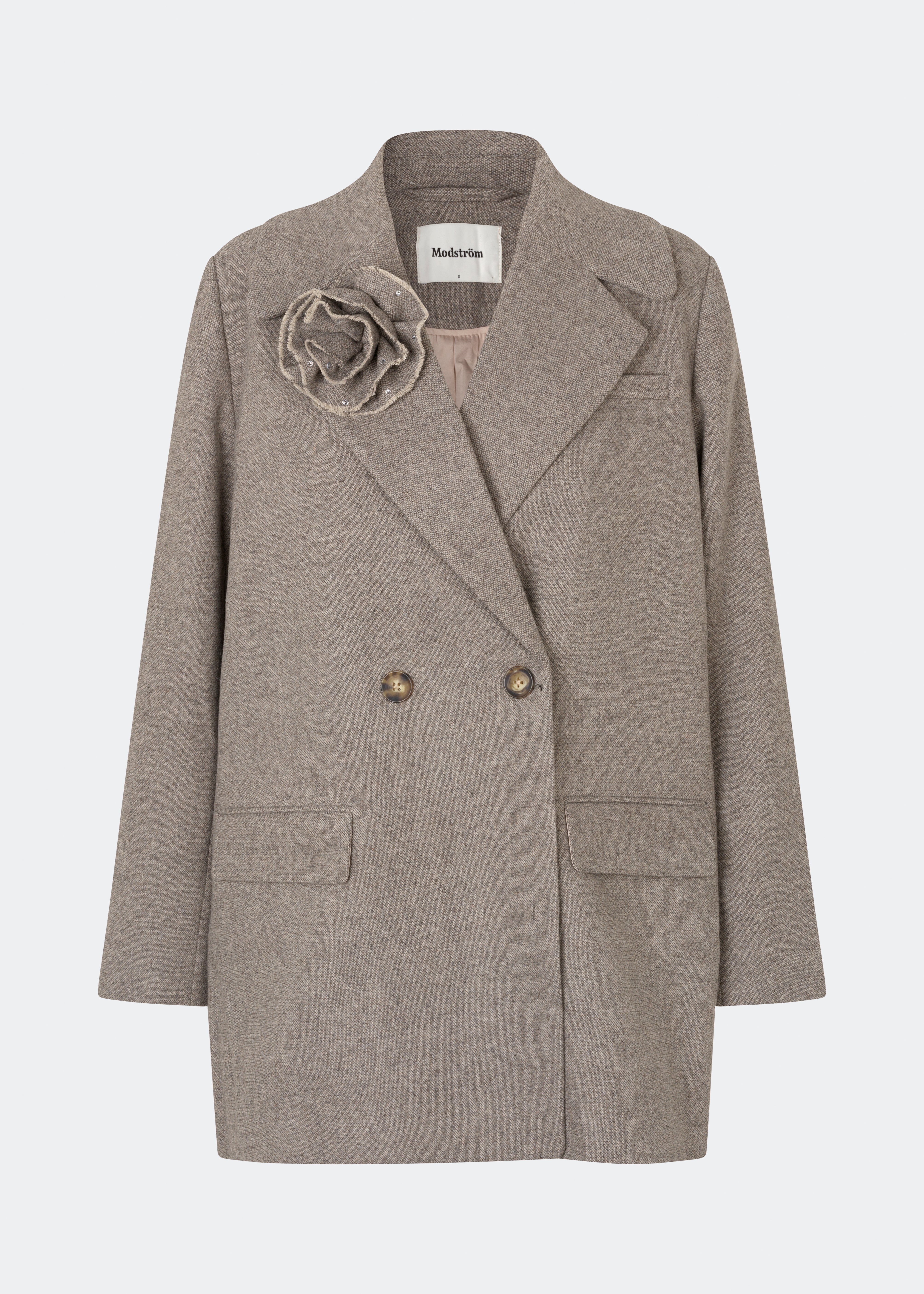 Cecarmd Jacket er en klassisk dobbeltradet jakke med en afslappet, oversized pasform. Designet er fuldendt med brede revers, klaplommer og en aftagelig blomsterbroche, som tilfører et feminint og dekorativt element. Den bløde uldblanding gør jakken ideel som overgangsjakke eller som et elegant lag over sæsonens strik og tailoring.