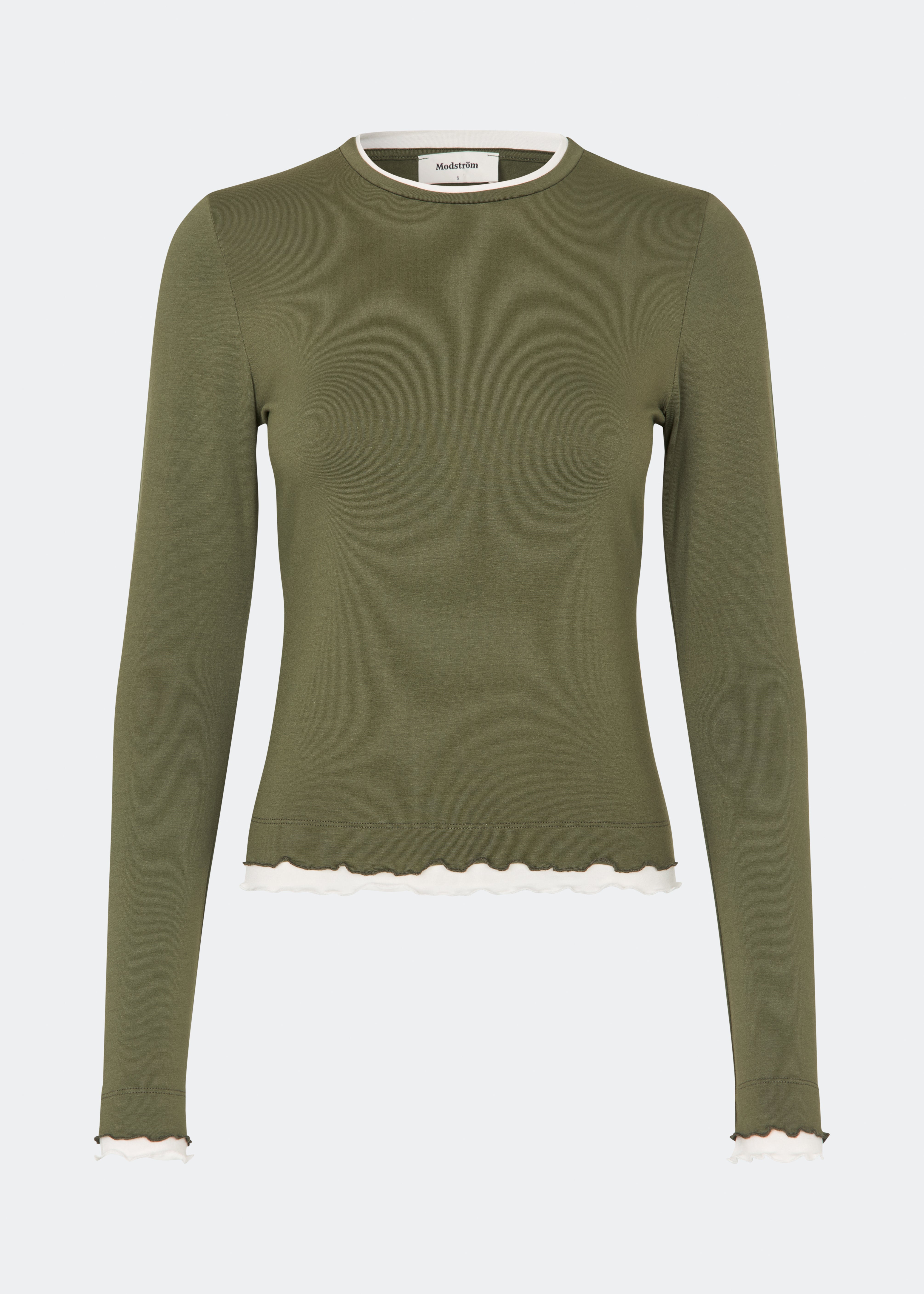 Langærmet T-shirt i en blød og komfortabel kvalitet. CiljaMD LS T-shirt har en tætsiddende silhuet med rund halsudskæring og dekorative kontrastkanter ved hals, manchetter og forneden, som skaber en lag-på-lag-effekt. De bølgede afslutninger tilfører et feminint touch til det enkle design, hvilket gør den perfekt både alene og som et lag under strik, skjorter eller jakker.