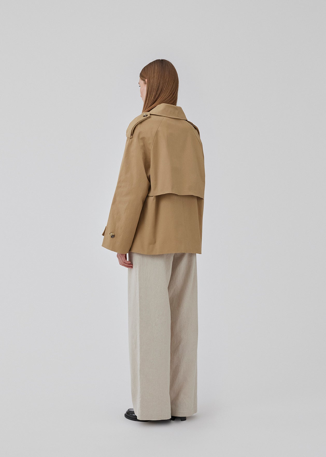 Populær kort trenchcoat i beige i bomuldskvalitet med skjult knaplukning fortil. Clara jacket har en oversize silhuet og klassiske detaljer. Med for. Modellen er 177 cm og har en størrelse S/36 på.