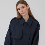 Kort trenchcoat i mørkeblå i bomuldskvalitet med skjult knaplukning fortil. Clara jacket har en oversize silhuet og klassiske detaljer. Med for.