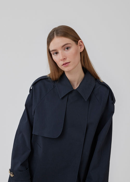 Kort trenchcoat i mørkeblå i bomuldskvalitet med skjult knaplukning fortil. Clara jacket har en oversize silhuet og klassiske detaljer. Med for.