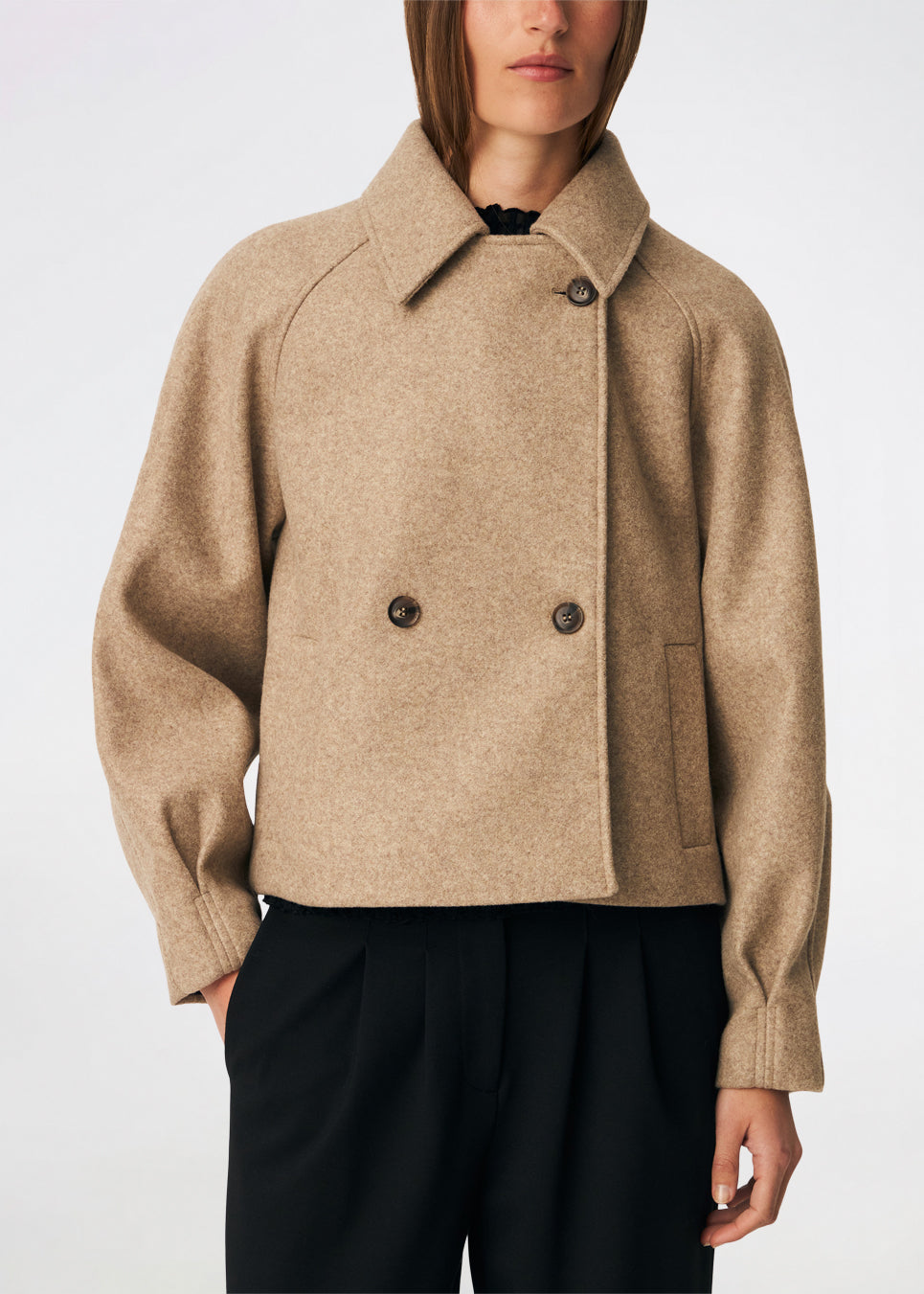 Kort uldjakke med et tidløst og sofistikeret udtryk. Cleamd jacket har en afslappet, let boxy silhuet med dobbeltradet knaplukning, klassisk krave og raglanærmer, der giver et blødt og komfortabelt fit. Diskrete stiklommer og rene linjer understreger det minimalistiske design, mens den korte længde gør jakken ideel til både hverdagsbrug og mere elegante outfits.