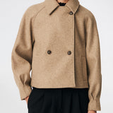 Kort uldjakke med et tidløst og sofistikeret udtryk. Cleamd jacket har en afslappet, let boxy silhuet med dobbeltradet knaplukning, klassisk krave og raglanærmer, der giver et blødt og komfortabelt fit. Diskrete stiklommer og rene linjer understreger det minimalistiske design, mens den korte længde gør jakken ideel til både hverdagsbrug og mere elegante outfits.