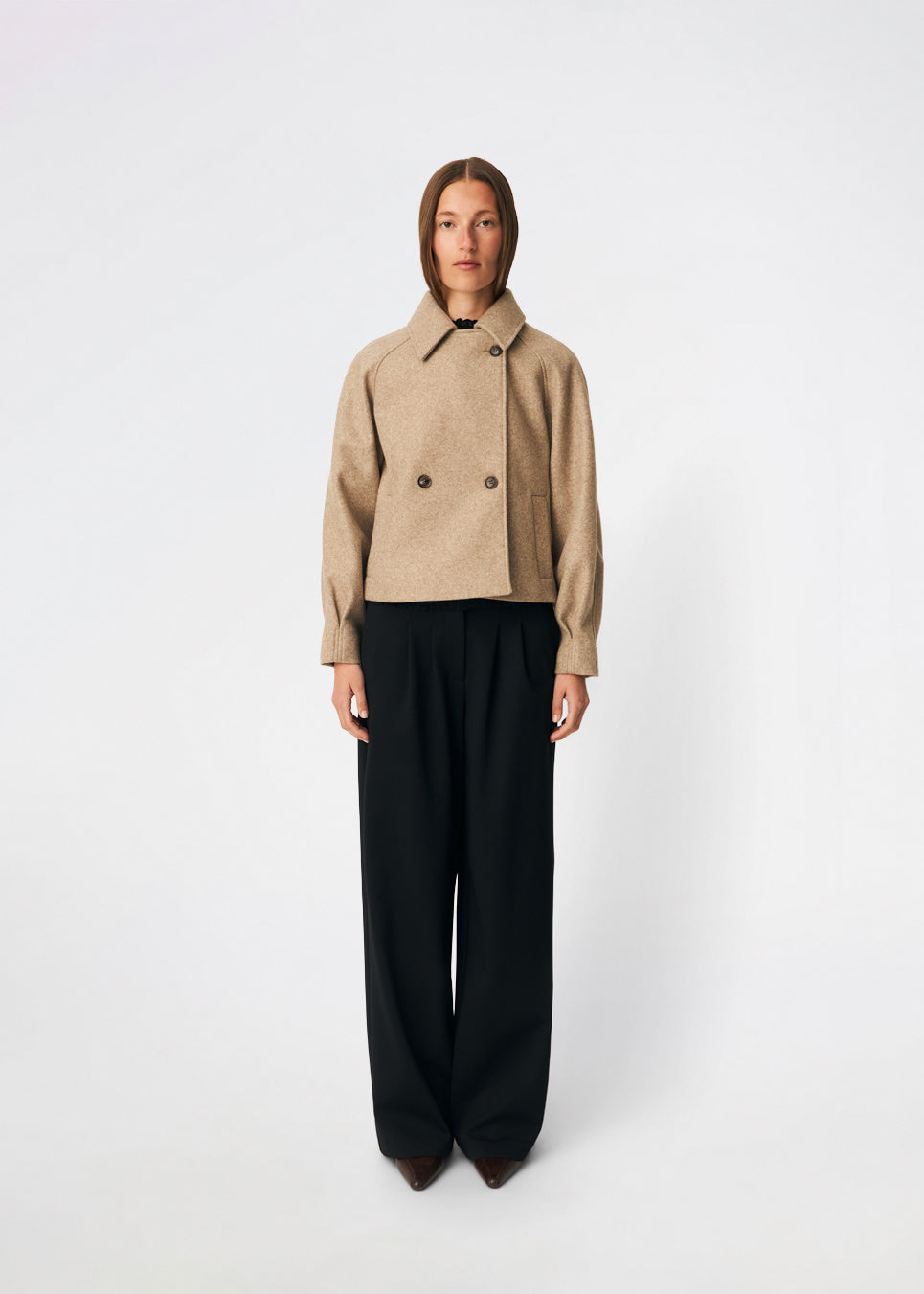 Kort uldjakke med et tidløst og sofistikeret udtryk. Cleamd jacket har en afslappet, let boxy silhuet med dobbeltradet knaplukning, klassisk krave og raglanærmer, der giver et blødt og komfortabelt fit. Diskrete stiklommer og rene linjer understreger det minimalistiske design, mens den korte længde gør jakken ideel til både hverdagsbrug og mere elegante outfits.