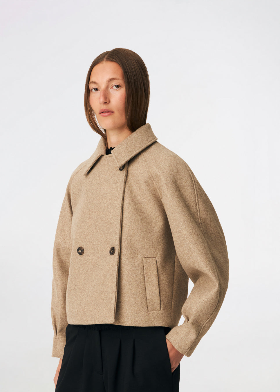 Kort uldjakke med et tidløst og sofistikeret udtryk. Cleamd jacket har en afslappet, let boxy silhuet med dobbeltradet knaplukning, klassisk krave og raglanærmer, der giver et blødt og komfortabelt fit. Diskrete stiklommer og rene linjer understreger det minimalistiske design, mens den korte længde gør jakken ideel til både hverdagsbrug og mere elegante outfits.