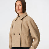 Kort uldjakke med et tidløst og sofistikeret udtryk. Cleamd jacket har en afslappet, let boxy silhuet med dobbeltradet knaplukning, klassisk krave og raglanærmer, der giver et blødt og komfortabelt fit. Diskrete stiklommer og rene linjer understreger det minimalistiske design, mens den korte længde gør jakken ideel til både hverdagsbrug og mere elegante outfits.