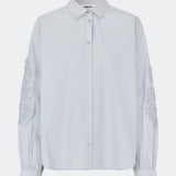 ColumbusMD Shirt er en skjorte med løs pasform og klassisk krave. Designet har gennemgående knaplukning, lange ærmer med manchetter og dekorative blomsterdetaljer langs ærmerne. Style den med jeans eller et par klassiske bukser til et enkelt hverdagslook. Modellen er 175 cm høj og bruger størrelse S/36.