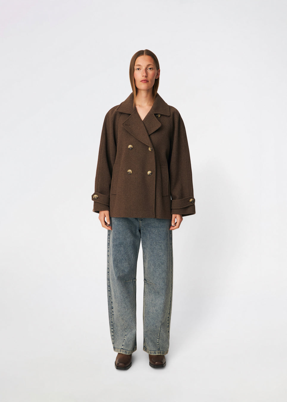 Kort dobbeltradet jakke i uldblanding. Brede revers og et bindebælte definerer formen, mens klaplommer afslutter fronten. Style den med bæltet lukket og jeans med lige ben eller åben over en flagrende kjole. Modellen er 175 cm høj og bruger størrelse S/36.