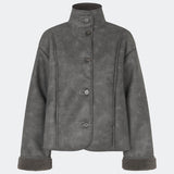 Kort jakke i imiteret rulam med et moderne og tidløst udtryk. Coralinemd jacket har en afslappet silhuet med høj ståkrave, knaplukning foran og dekorative syningsdetaljer, der fremhæver det klassiske design. De bløde teddykanter ved ærmerne tilfører varme og kontrast, mens den let oversized pasform gør jakken ideel til lag-på-lag styling gennem de kolde måneder.