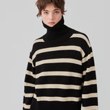 Finstrikket, oversized trøje i bomuldsstrik i sort med beige striber. CorbinMD stripe t-neck har en ribstrikket rullekrave, lange brede ærmer og brede ribkanter ved ærmer og forneden. Modellen er 177 cm og har en størrelse S/36 på.