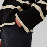 Finstrikket, oversized trøje i bomuldsstrik i sort med beige striber. CorbinMD stripe t-neck har en ribstrikket rullekrave, lange brede ærmer og brede ribkanter ved ærmer og forneden. Modellen er 177 cm og har en størrelse S/36 på.