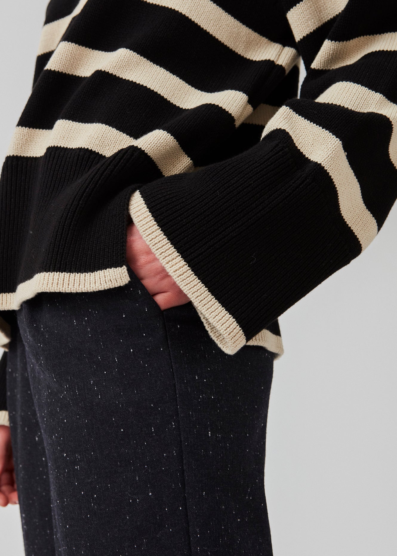 Finstrikket, oversized trøje i bomuldsstrik i sort med beige striber. CorbinMD stripe t-neck har en ribstrikket rullekrave, lange brede ærmer og brede ribkanter ved ærmer og forneden. Modellen er 177 cm og har en størrelse S/36 på.