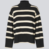 Finstrikket, oversized trøje i bomuldsstrik i sort med beige striber. CorbinMD stripe t-neck har en ribstrikket rullekrave, lange brede ærmer og brede ribkanter ved ærmer og forneden. Modellen er 177 cm og har en størrelse S/36 på.
