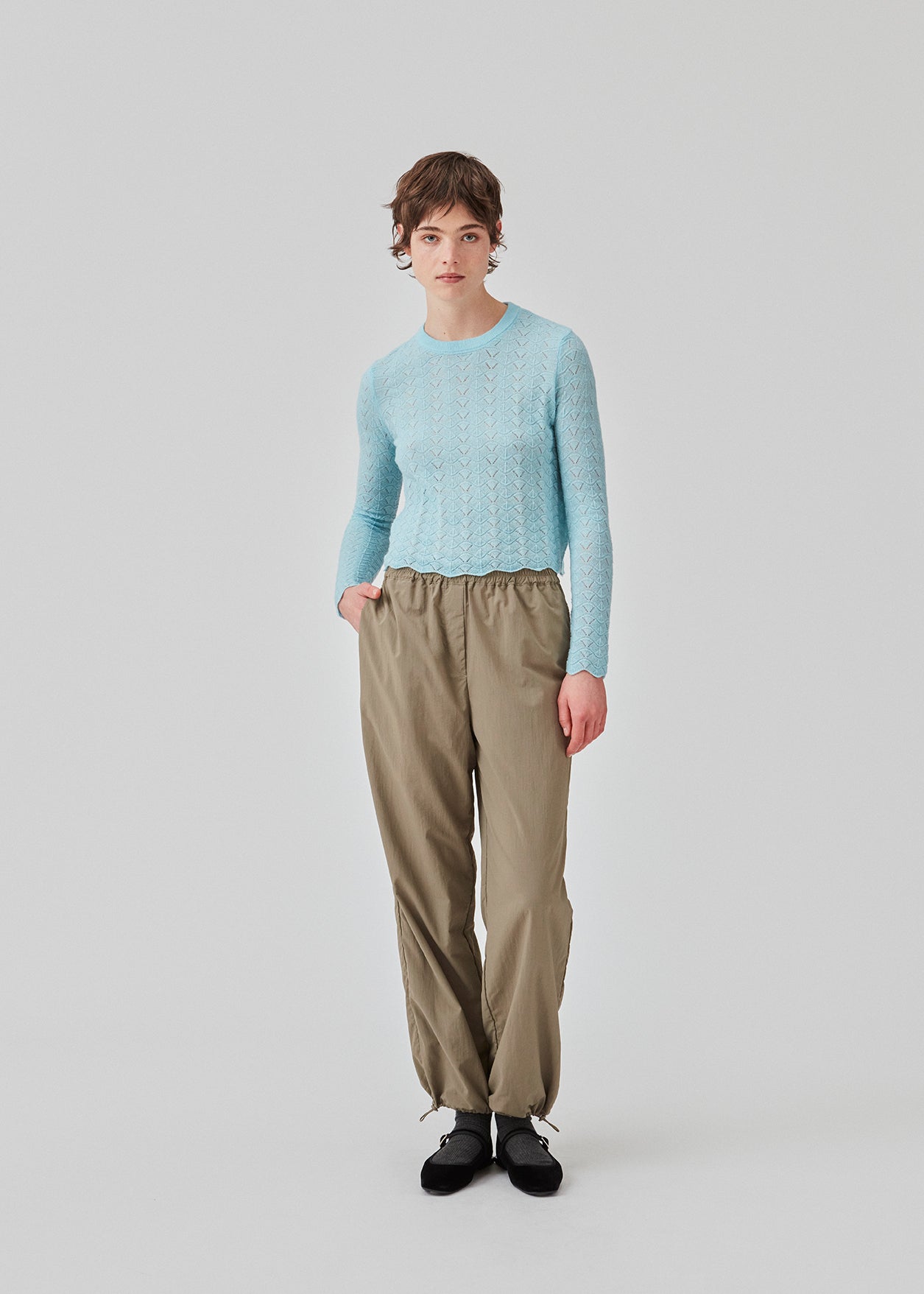 Strikket trøje i lyseblå med hulmønster i let kvalitet med uld. CordellMD short o-neck har en afslappet cropped pasform og lange ærmer med bølgede kanter. Modellen er 175 cm og har en størrelse S/36 på.