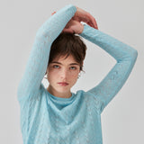 Strikket trøje i lyseblå med hulmønster i let kvalitet med uld. CordellMD short o-neck har en afslappet cropped pasform og lange ærmer med bølgede kanter. Modellen er 175 cm og har en størrelse S/36 på.