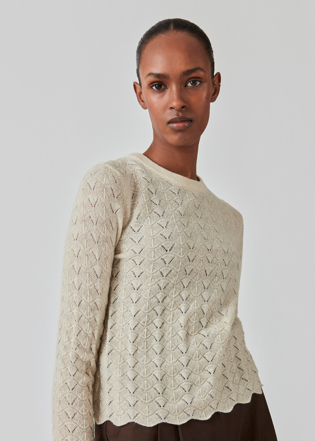 Strikket trøje i beige med hulmønster i let kvalitet med uld. CordellMD short o-neck har en afslappet cropped pasform og lange ærmer med bølgede kanter. Modellen er 175 cm og har en størrelse S/36 på.