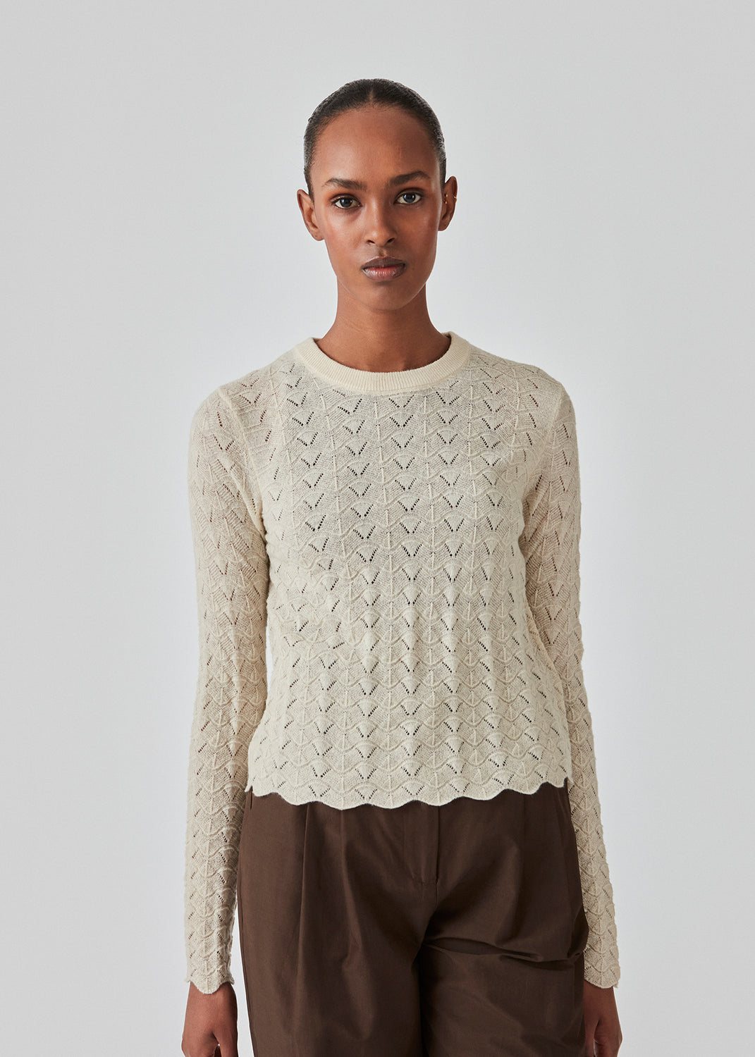 Strikket trøje i beige med hulmønster i let kvalitet med uld. CordellMD short o-neck har en afslappet cropped pasform og lange ærmer med bølgede kanter. Modellen er 175 cm og har en størrelse S/36 på.