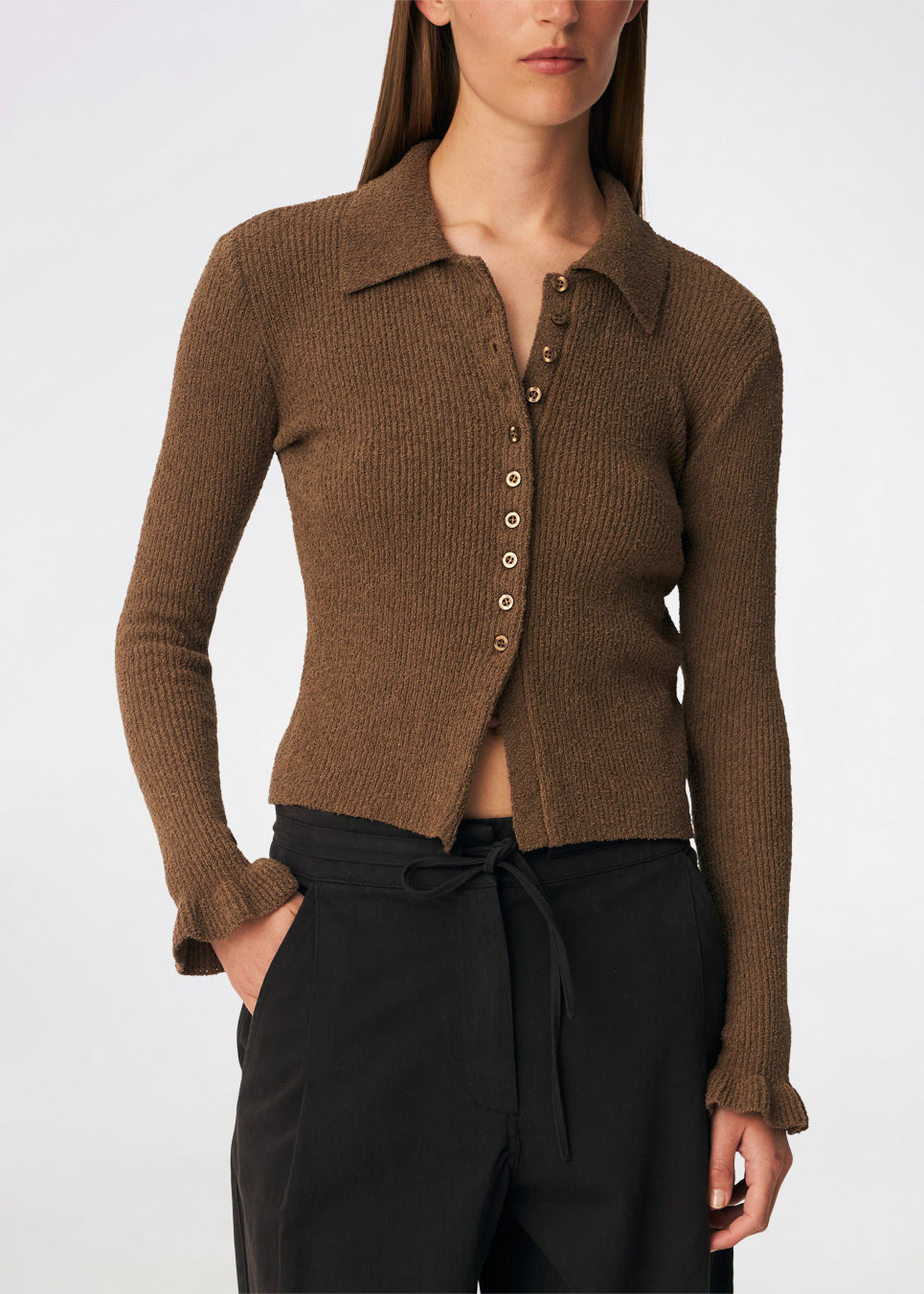 Feminin ribstrikket cardigan med elegante detaljer. Corneliamd cardigan er designet i en tætsiddende silhuet med klassisk krave, gennemgående knaplukning og fine flæsekantdetaljer ved manchetterne. 