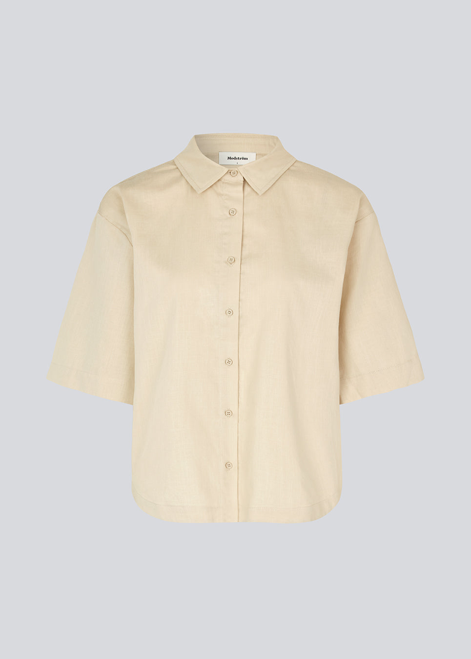 Kort, oversized skjorte i beige i bomuld. CydneyMD ss shirt har krave, knaplukning fortil og afrundede kanter forneden. Lav skuldersøm og korte ærmer. Modellen er 175 cm og har en størrelse S/36 på.