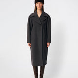 Cyllemd Coat er en lang, oversized frakke med et tidløst og minimalistisk udtryk. Frakken er designet med brede revers, skjult knaplukning og diskrete paspolerede lommer, som giver et rent og sofistikeret look. Den afslappede silhuet gør den nem at style over både skræddersyede outfits og afslappede hverdagslooks, mens den bløde uldblanding sikrer komfort gennem hele sæsonen.