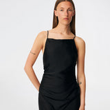 DanillaMD Dress er en lang satin-kjole med en elegant, figurnær silhuet. Designet har en lige halsudskæring, tynde stropper og draperede detaljer i siden, som skaber et blødt fald. Den åbne ryg med fine krydsende stropper tilfører et feminint udtryk. Style den med hæle og enkle accessories til særlige anledninger. Modellen er 175 cm høj og bruger størrelse S/36.