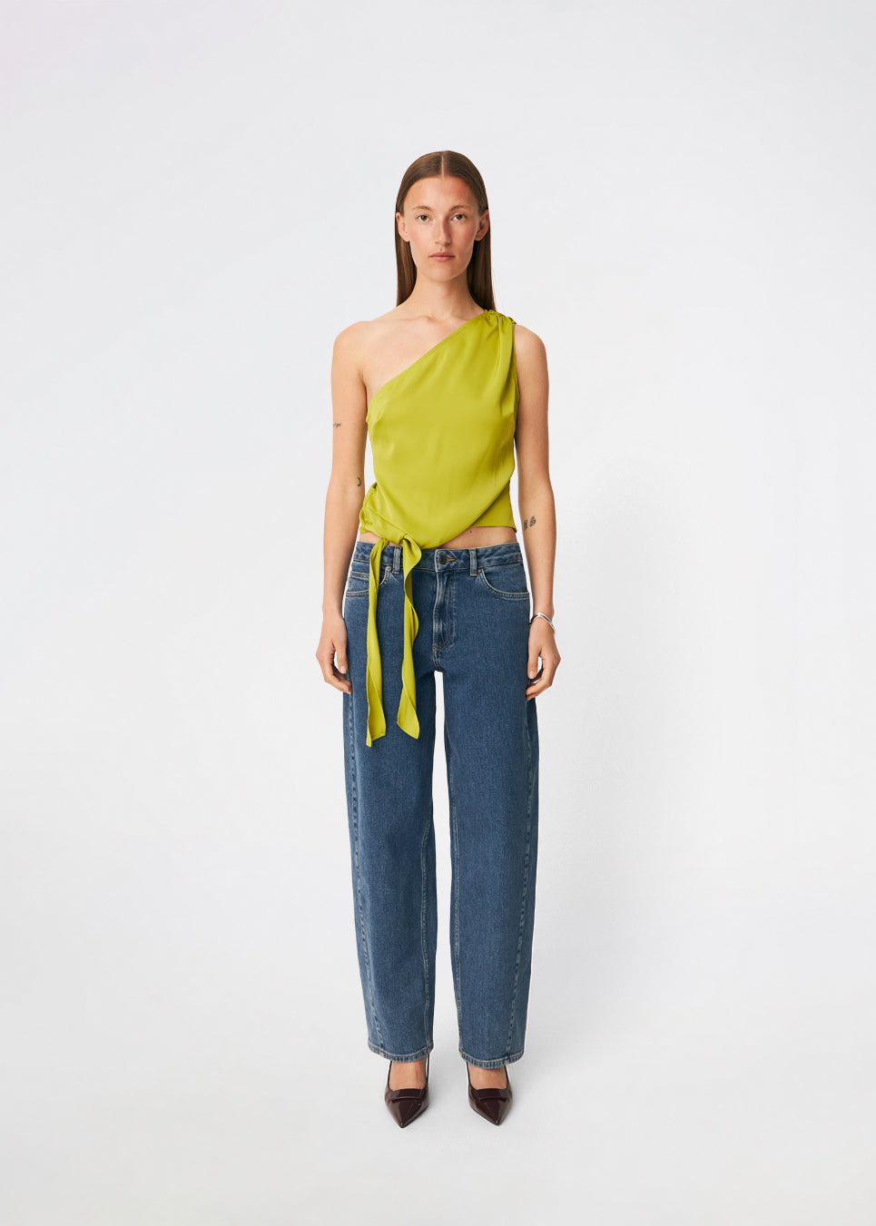 DanillaMD Top er en asymmetrisk satin-top med en tætsiddende silhuet og én skulder. Designet har bløde draperinger og bindebånd i siden, som skaber en feminin detalje og giver mulighed for at justere pasformen. Style den med skræddersyede bukser eller en lang nederdel til både hverdag og særlige anledninger. Modellen er 175 cm høj og bruger størrelse S/36.