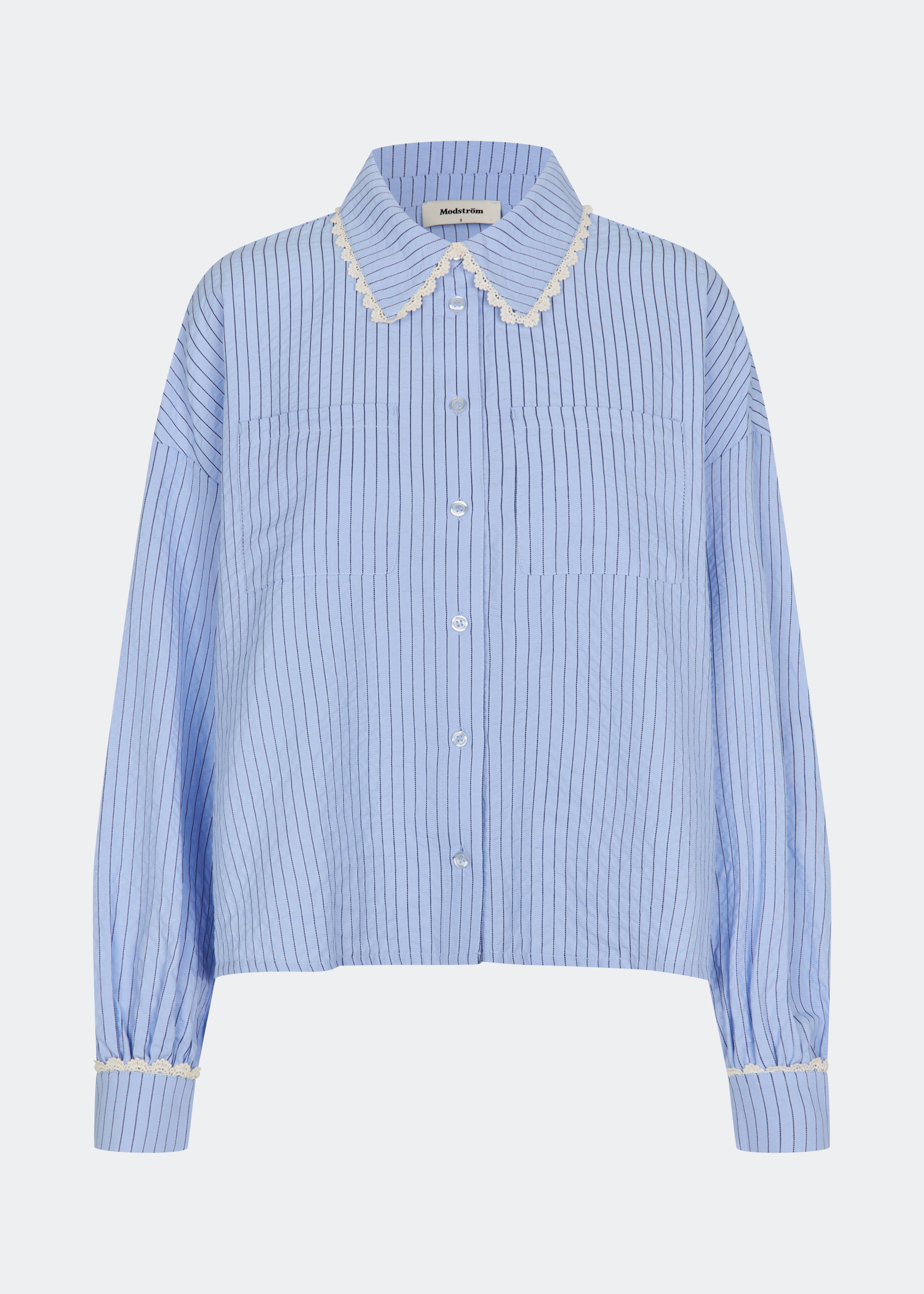 DanjaMD Shirt er en stribet skjorte med en afslappet pasform og lange ærmer. Designet har klassisk skjortekrave med dekorativ blondekant, knaplukning foran og to brystlommer. Blondekanter ved manchetterne tilfører en feminin kontrast til det klassiske stribede udtryk. Style den med jeans eller skræddersyede bukser til hverdagsbrug. Modellen er 175 cm høj og bruger størrelse S/36.