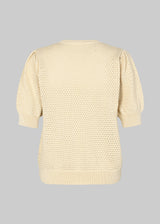 DariaMD o-neck er en hulstrikket trøje i beige med korte pufærmer og rund hals. Ribkanter forneden, i halsen og ved manchetterne. Modellen er 177 cm og har en størrelse S/36 på.
