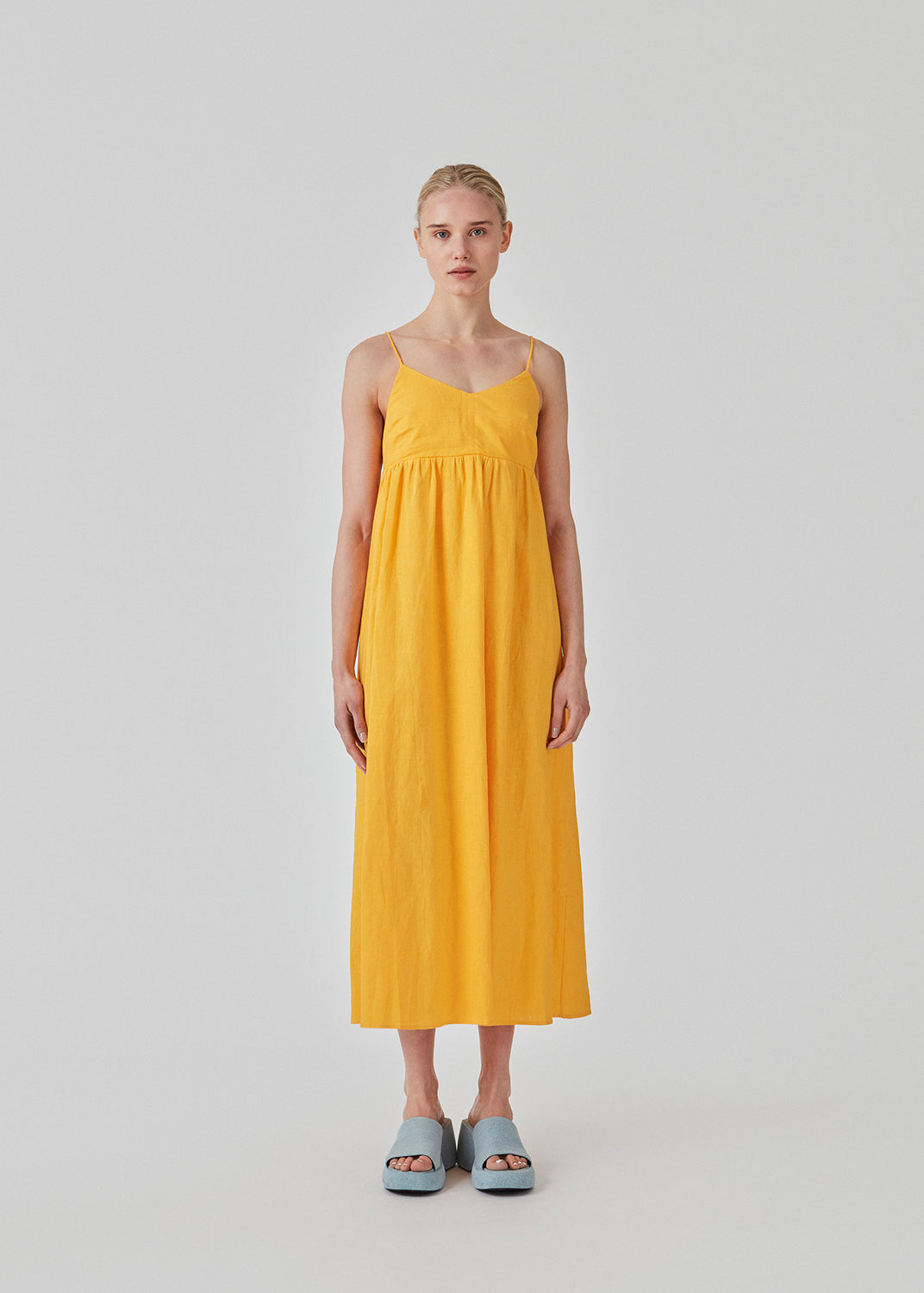DarrelMD long dress i gul er designet i et hør mix med en tætsiddende top med v-udskæring, spaghettistropper med justerbart bindebånd bagpå og løst skørt. Med for. Modellen er 177 cm og har en størrelse S/36 på.