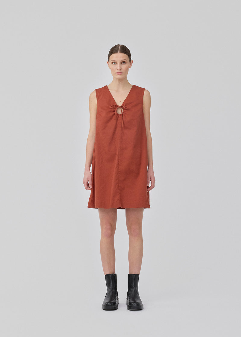 Kort mørkerød kjole i hørkvalitet med A-facon. DaynaMD dress er uden ærmer, med dyb v-udskæring med cut out-detalje og bindebånd. Modellen er 177 cm og har en størrelse S/36 på.