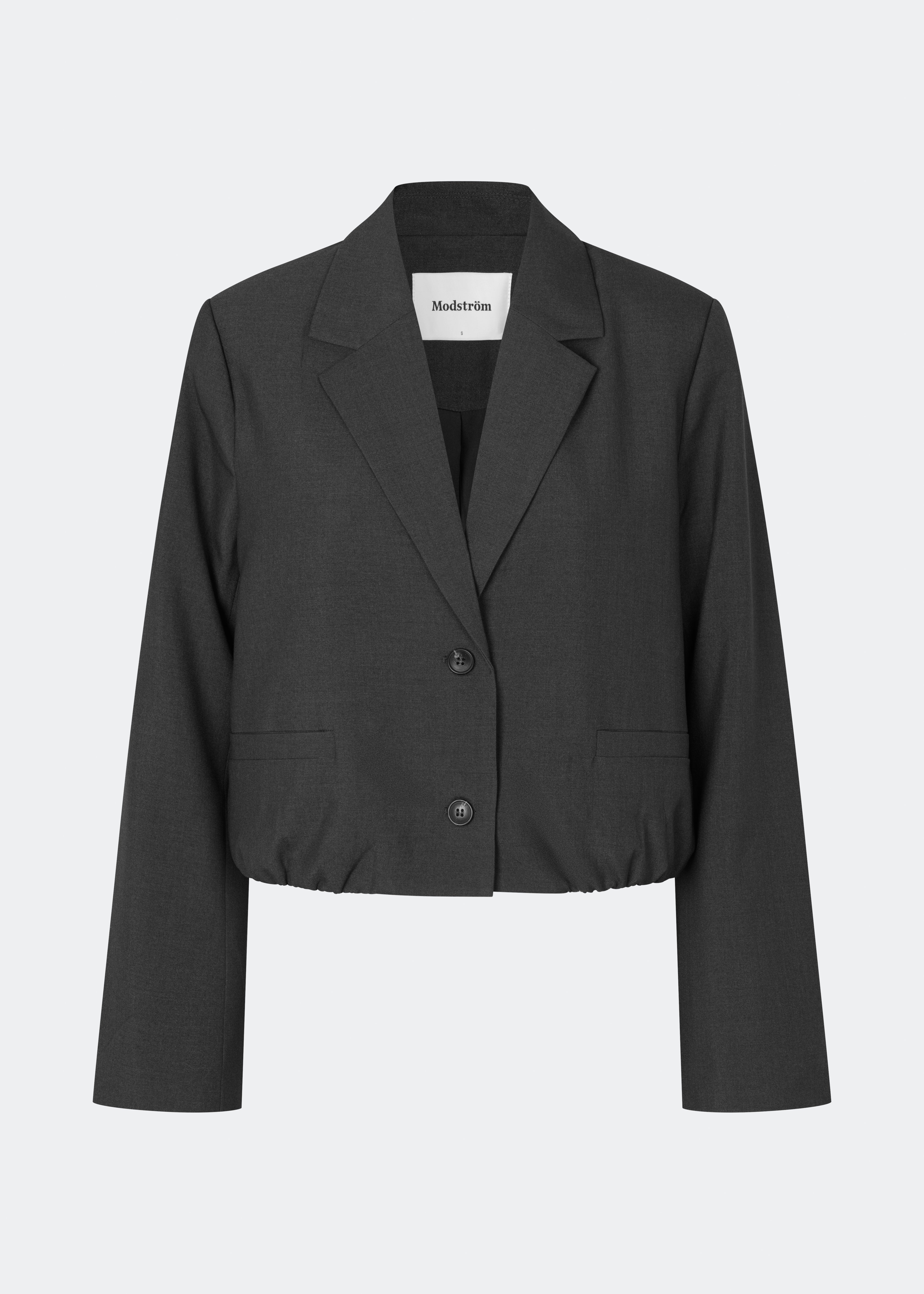 DeanneMD Blazer er en kort blazer med en afslappet, moderne silhuet. Blazeren har klassisk revers, lange ærmer, to knapper foran og elastisk kant forneden, der giver den skræddersyede style et mere casual udtryk. Style den med matchende bukser for et komplet suit-look eller med jeans for en mere afslappet styling. Modellen er 175 cm høj og bruger størrelse S/36.