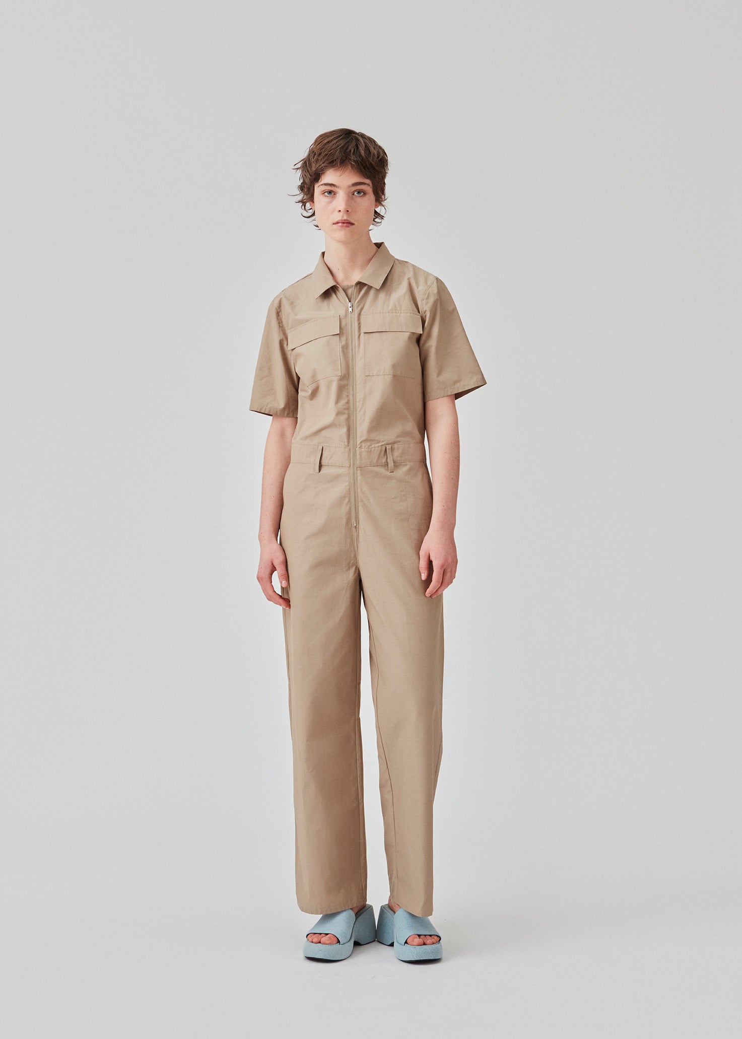 Jumpsuit i sprød bomuldskvalitet med lange, brede ben. DedeMD jumpsuit har korte ærmer, krave, og lynlås foran. Bæltestropper i taljen. Modellen er 177 cm og har en størrelse S/36 på.
