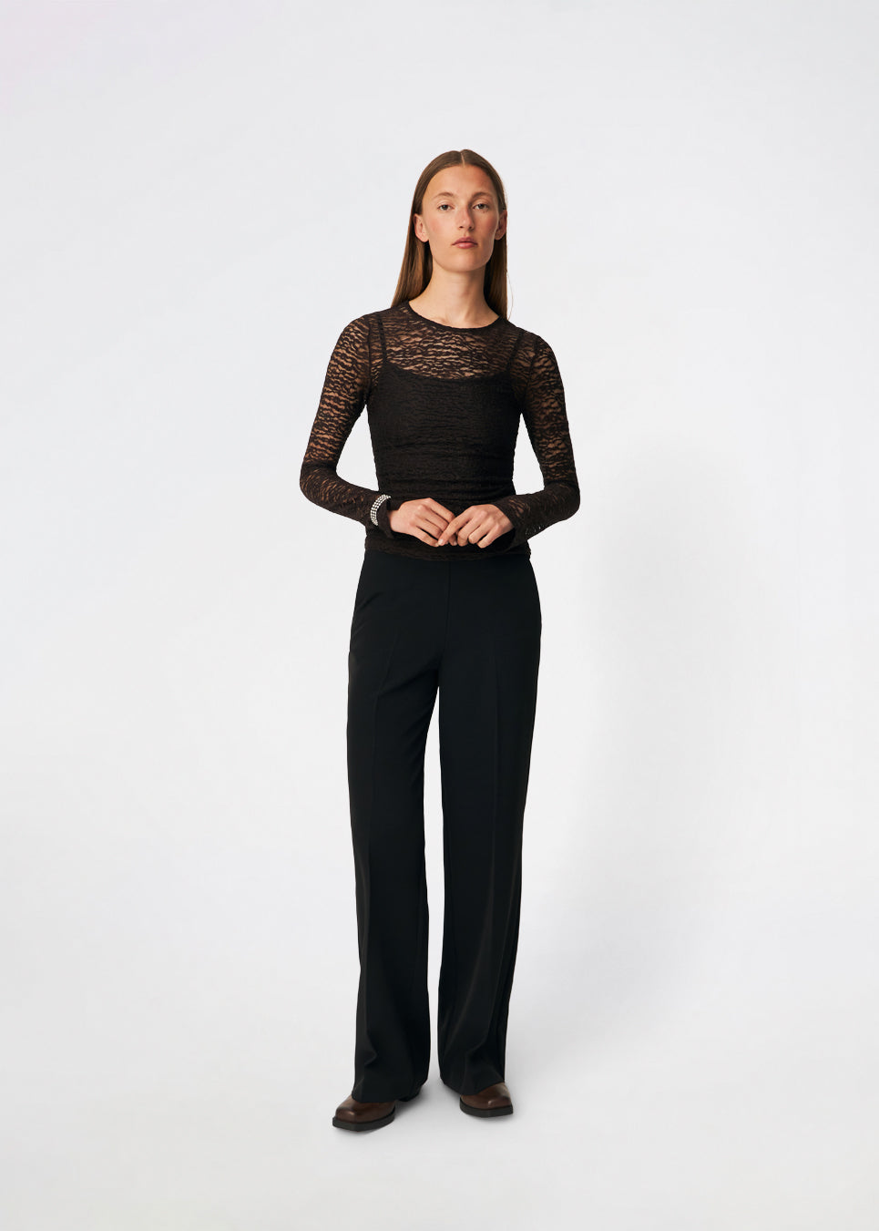 Dianamd Top er en tætsiddende blondetop med lange ærmer og et transparent udtryk, der tilfører garderoben et feminint og moderne touch. Den enkle silhuet gør den nem at style alene eller som et lag under blazere, strik eller kjoler, hvor blondedetaljerne får lov at træde frem. Perfekt til både hverdagslooks og særlige anledninger. Modellen er 175 cm høj og bruger størrelse S/36.
