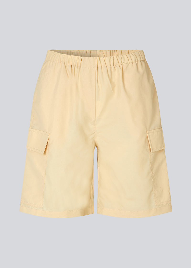 Cargo shorts i farven Pale Sun i nylon med brede ben. DilaraMD shorts har beklædt elastik i taljen og to store påsatte lommer på siden. Modellen er 177 cm og har en størrelse S/36 på.