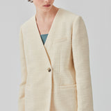 DimeMD blazer er designet i et tekstureret bomuldsmix med foer. Blazeren er uden krave og revers, men har en asymmetrisk wrap-detalje med en enkelt synlig knap. Modellen er 177 cm og har en størrelse S/36 på.  Style blazeren med matchende shorts: DimeMD shorts.