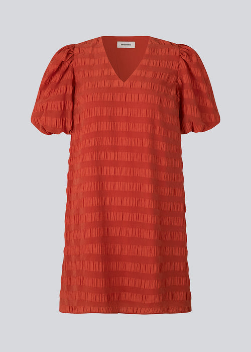 Kort kjole i rød designet i et bæk og bølge materiale. DinoMD dress har v-udskæring i halsen, en løs pasform og korte puffærmer med elastik. Modellen er 177 cm og har en størrelse S/36 på.