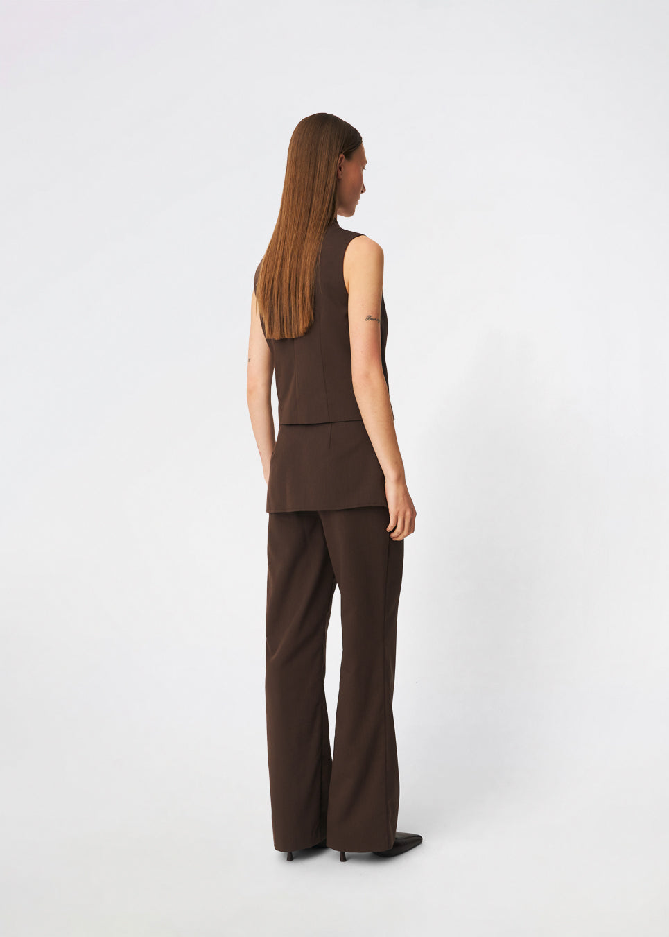 Dodomd Top er en elegant, ærmeløs top med en skarp silhuet og et moderne udtryk. Den høje hals med dekorative trykknapper og den skjulte frontlukning giver et rent, minimalistisk look, mens de figurskabende sømme fremhæver pasformen. Style den alene eller sammen med de matchende bukser for et sofistikeret sæt.