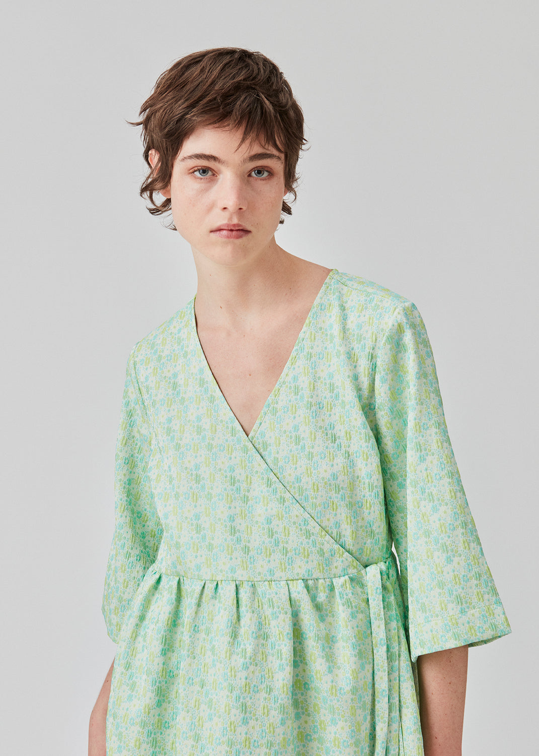 Kort kjole i struktureret materiale. DorianMD wrap dress har v-halsudskæring, brede ærmer i albuelængde og bindelukning. Modellen er 177 cm og har en størrelse S/36 på.