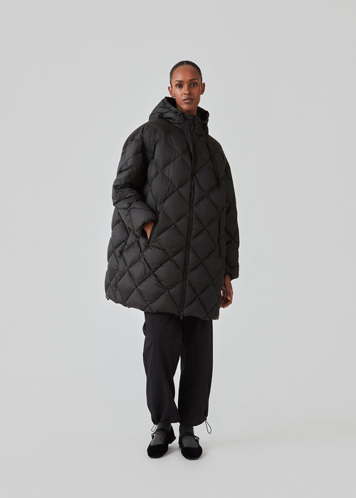 EddaMD jacket er en quiltet dunjakke med normal pasform. EddaMD jacket har høj krave med hætte med brede træksnore. Store lynlåse foran og på lommerne. Modellen er 175 cm og har en størrelse S/36 på.