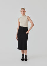 Midi-nederdel i sort i sprød vævet kvalitet. EmeryMD skirt har to påsatte lommer og slidser i begge sider. Modellen er 175 cm og har en størrelse S/36 på.