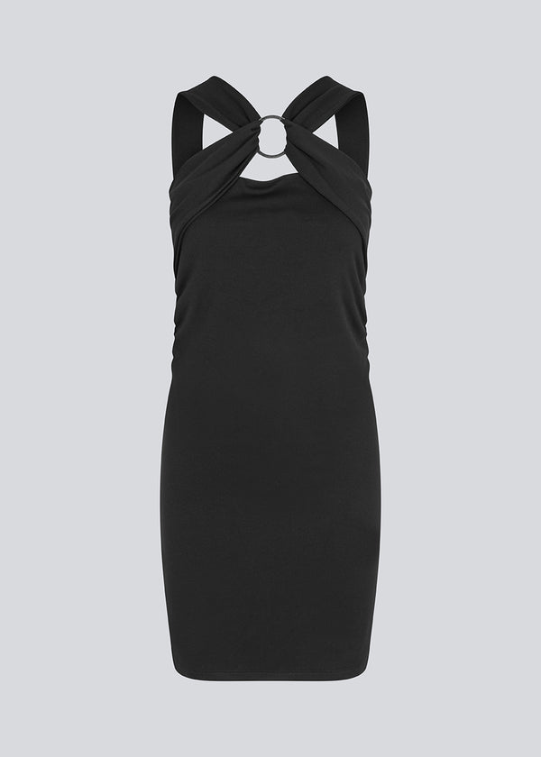 Kort figursyet sort kjole i et elastisk materiale. EmiliaMD dress har en super fed detalje med en metalring ved brystet og brede stropper.