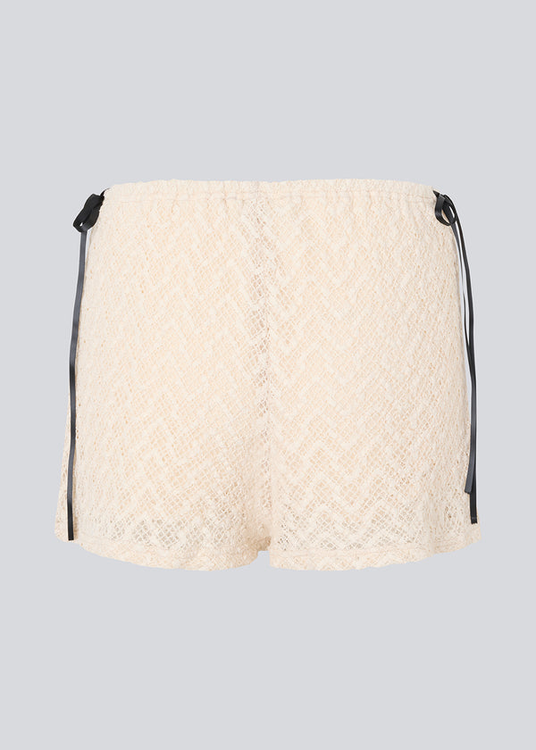 Løse shorts i fin beige/hvid farve i blødt blonde materiale. EmiliaMD lace shorts har foer og elastik i taljen. Sød detalje på hofterne med små sorte sløjfer, der har en cool kontrast til den lyse beige farve.