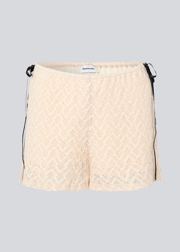Løse shorts i fin beige/hvid farve i blødt blonde materiale. EmiliaMD lace shorts har foer og elastik i taljen. Sød detalje på hofterne med små sorte sløjfer, der har en cool kontrast til den lyse beige farve.