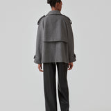 Cropped dobbeltradet uldfrakke med skjulte knapper. EsmundMD jacket i farven Dark Grey Melange har klassiske frakkedetaljer med raglanærmer og bredt bærestykke på ryggen. Med foer. Modellen er 175 cm og har en størrelse S/36 på.
