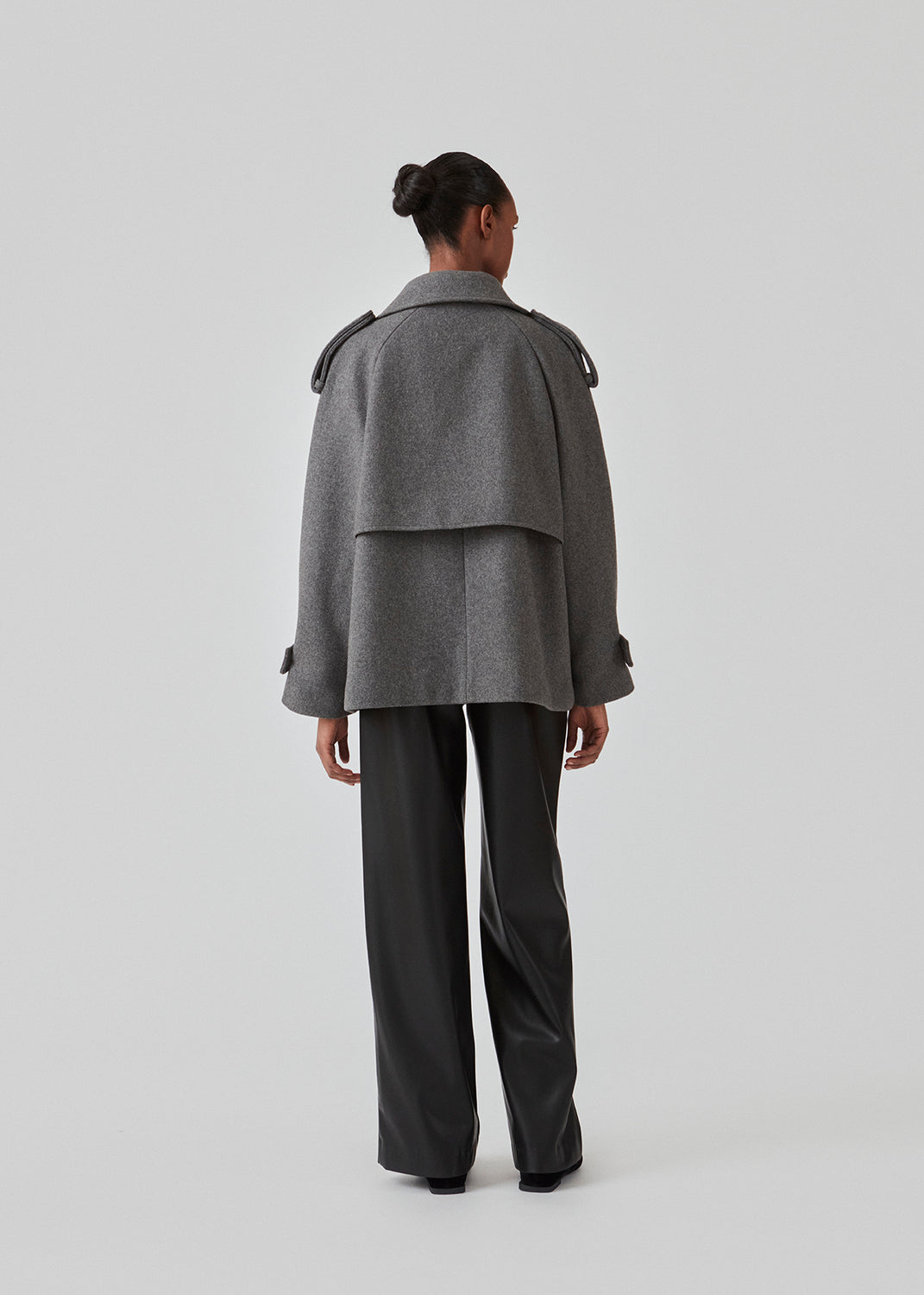 Cropped dobbeltradet uldfrakke med skjulte knapper. EsmundMD jacket i farven Dark Grey Melange har klassiske frakkedetaljer med raglanærmer og bredt bærestykke på ryggen. Med foer. Modellen er 175 cm og har en størrelse S/36 på.