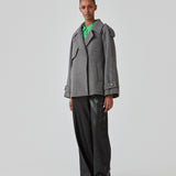 Cropped dobbeltradet uldfrakke med skjulte knapper. EsmundMD jacket i farven Dark Grey Melange har klassiske frakkedetaljer med raglanærmer og bredt bærestykke på ryggen. Med foer. Modellen er 175 cm og har en størrelse S/36 på.